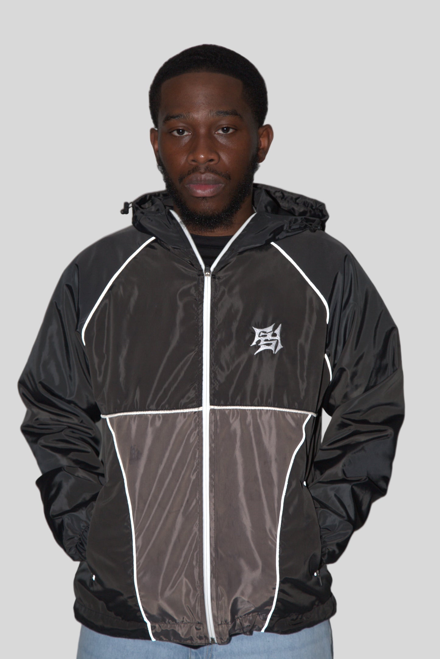 Person wearing a black jacket with white accents on a plain background