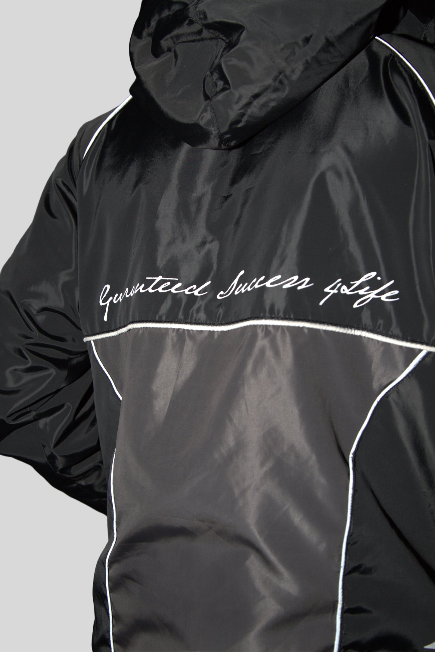 A black windbreaker with white text and detailing. The text reads ' Guaranteed Success Life '.